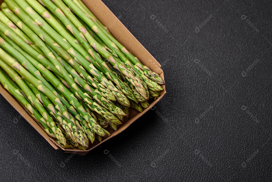Deliciosos raminhos frescos de aspargos em um fundo escuro texturizado. Ingredientes para uma refeição vegetariana saudável