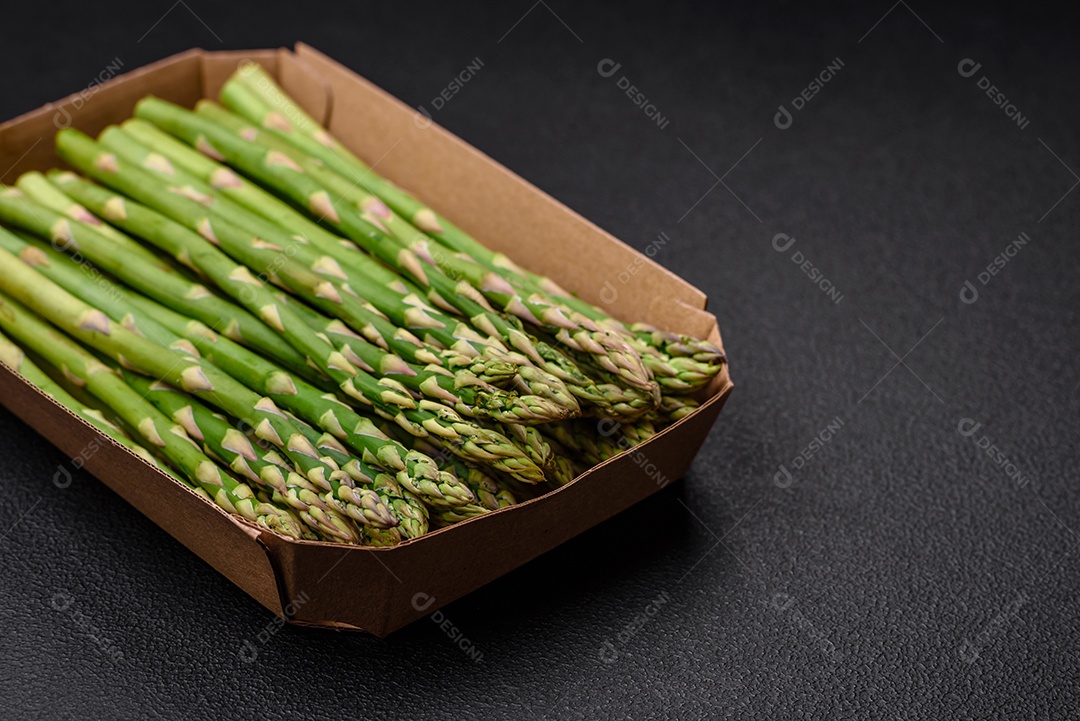 Deliciosos raminhos frescos de aspargos em um fundo escuro texturizado. Ingredientes para uma refeição vegetariana saudável