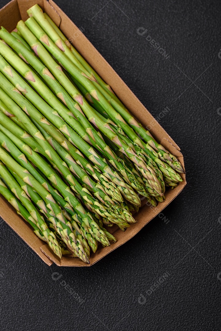 Deliciosos raminhos frescos de aspargos em um fundo escuro texturizado. Ingredientes para uma refeição vegetariana saudável
