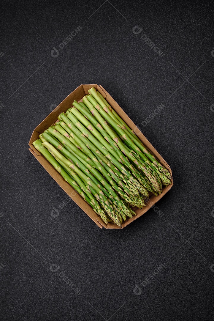 Deliciosos raminhos frescos de aspargos em um fundo escuro texturizado. Ingredientes para uma refeição vegetariana saudável