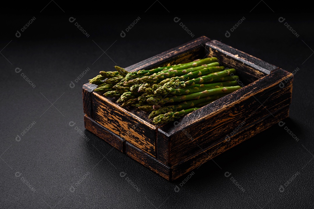 Deliciosos raminhos frescos de aspargos em um fundo escuro texturizado. Ingredientes para uma refeição vegetariana saudável
