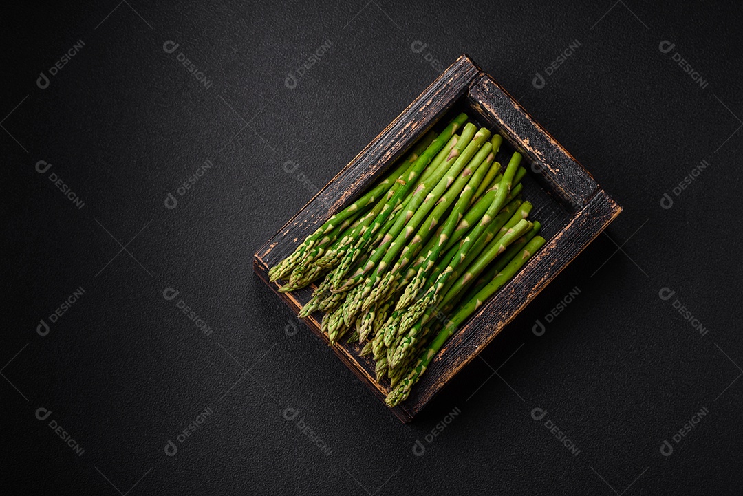 Deliciosos raminhos frescos de aspargos em um fundo escuro texturizado. Ingredientes para uma refeição vegetariana saudável