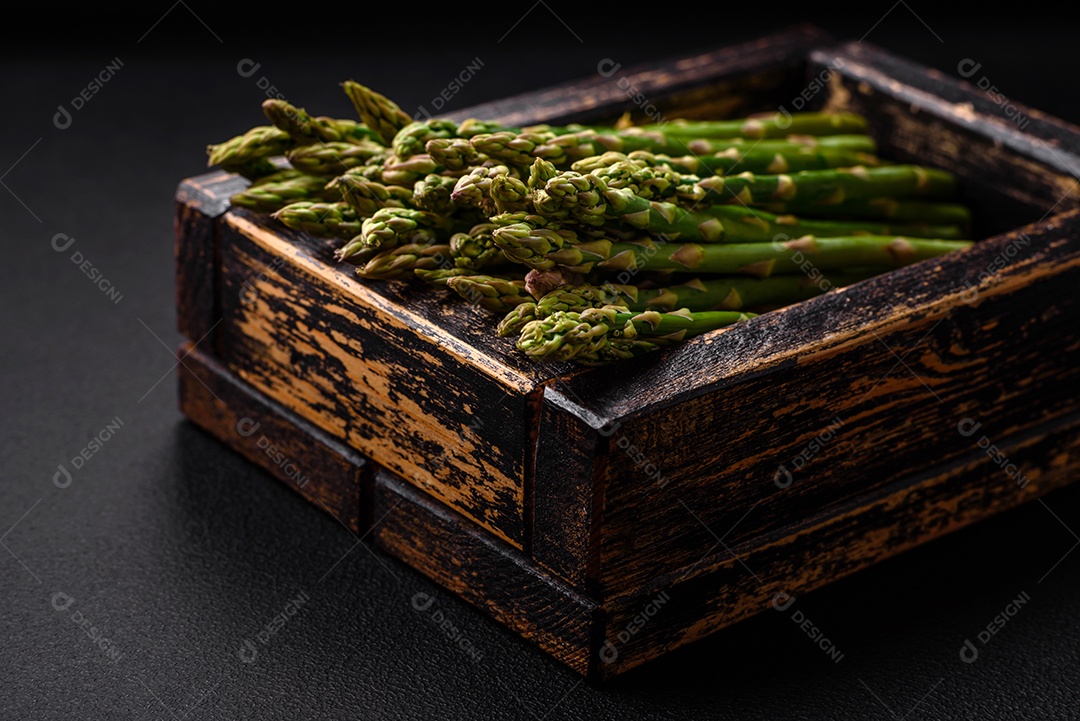 Deliciosos raminhos frescos de aspargos em um fundo escuro texturizado. Ingredientes para uma refeição vegetariana saudável