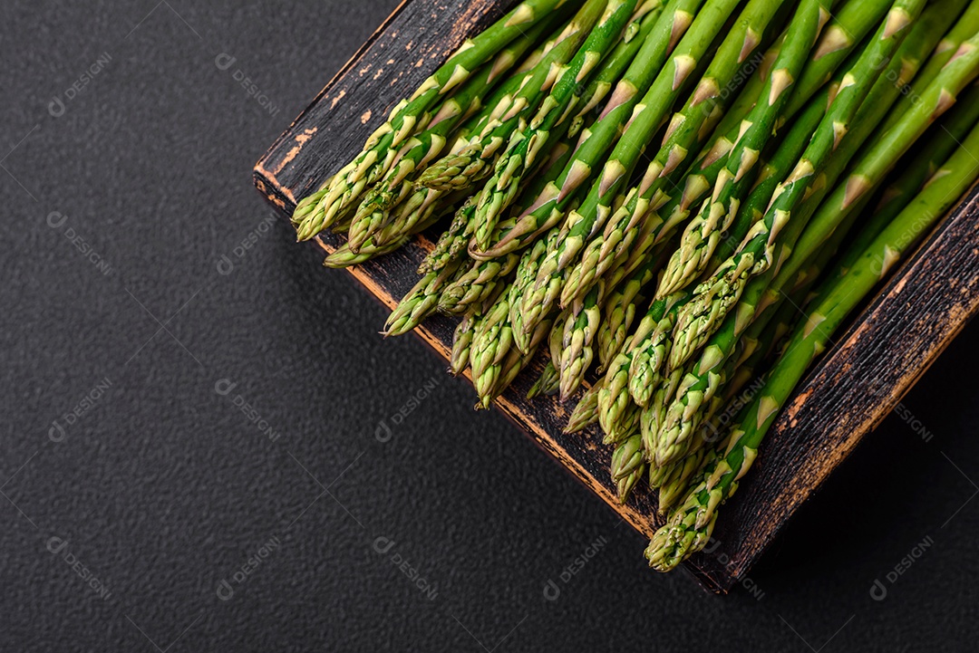 Deliciosos raminhos frescos de aspargos em um fundo escuro texturizado. Ingredientes para uma refeição vegetariana saudável