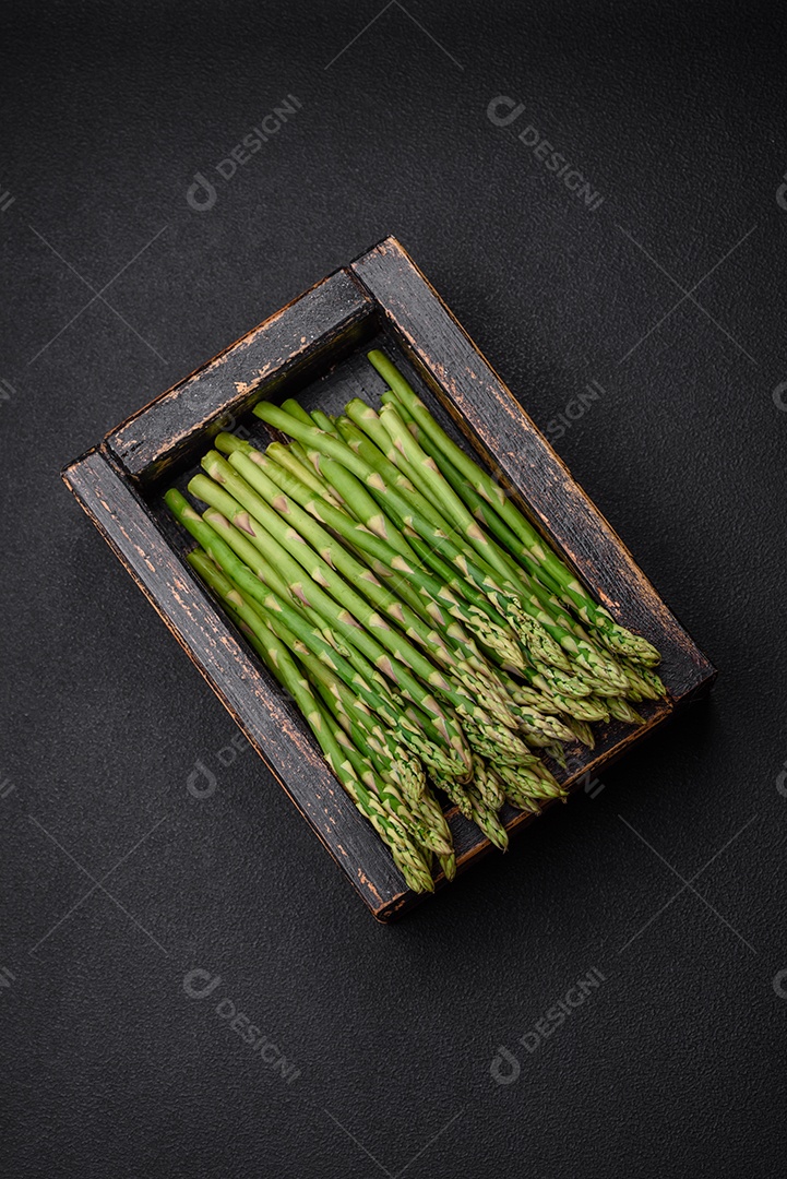 Deliciosos raminhos frescos de aspargos em um fundo escuro texturizado. Ingredientes para uma refeição vegetariana saudável