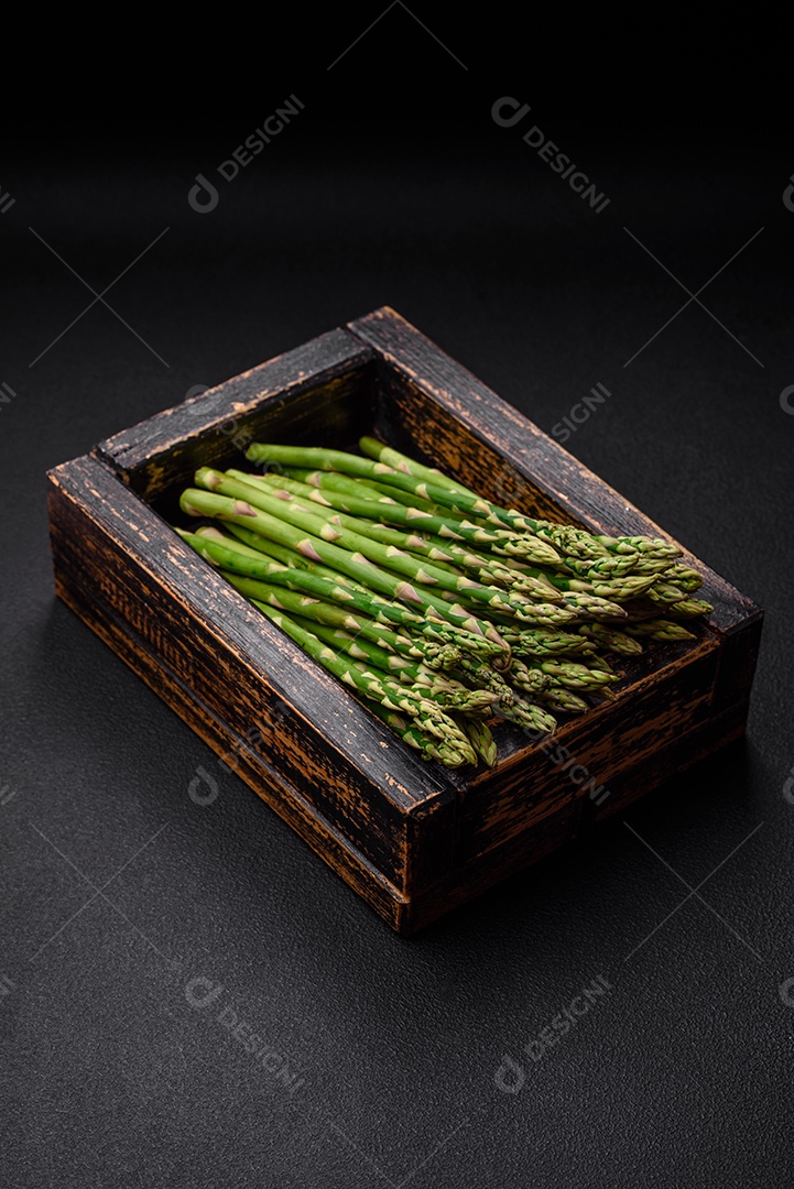Deliciosos raminhos frescos de aspargos em um fundo escuro texturizado. Ingredientes para uma refeição vegetariana saudável