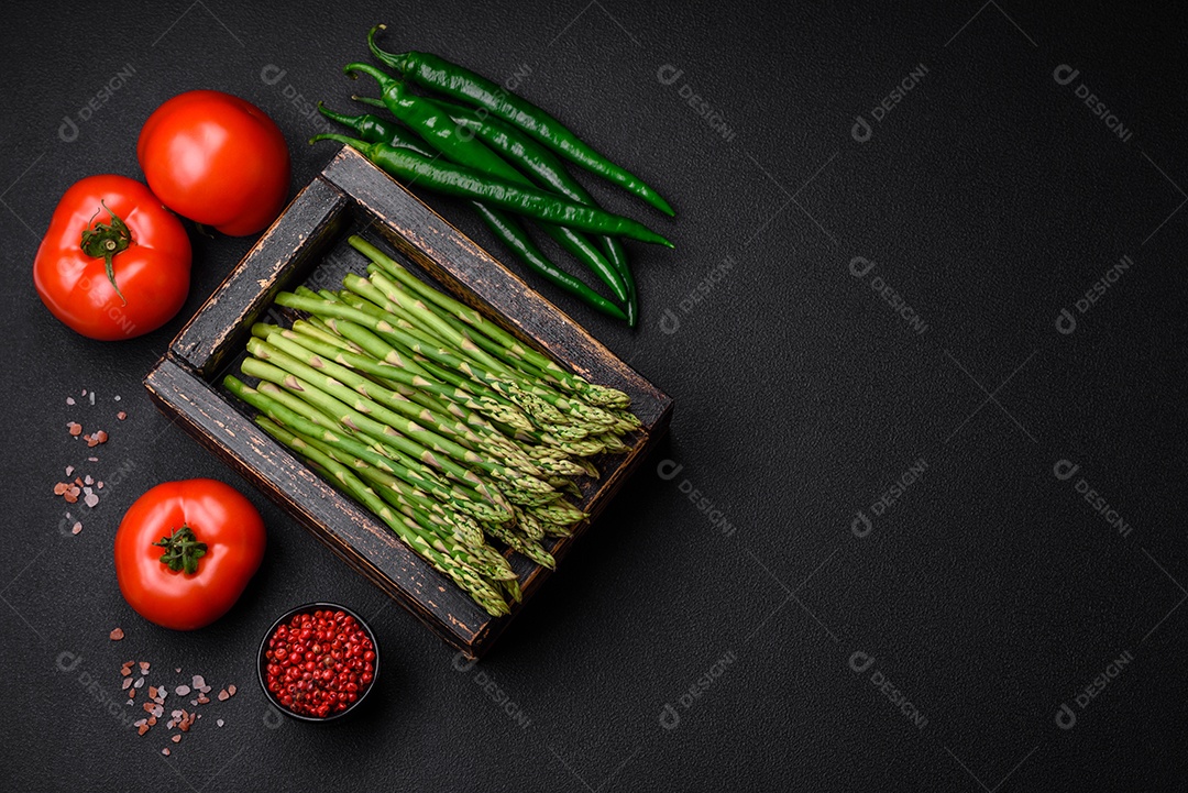 Deliciosos raminhos frescos de aspargos em um fundo escuro texturizado. Ingredientes para uma refeição vegetariana saudável
