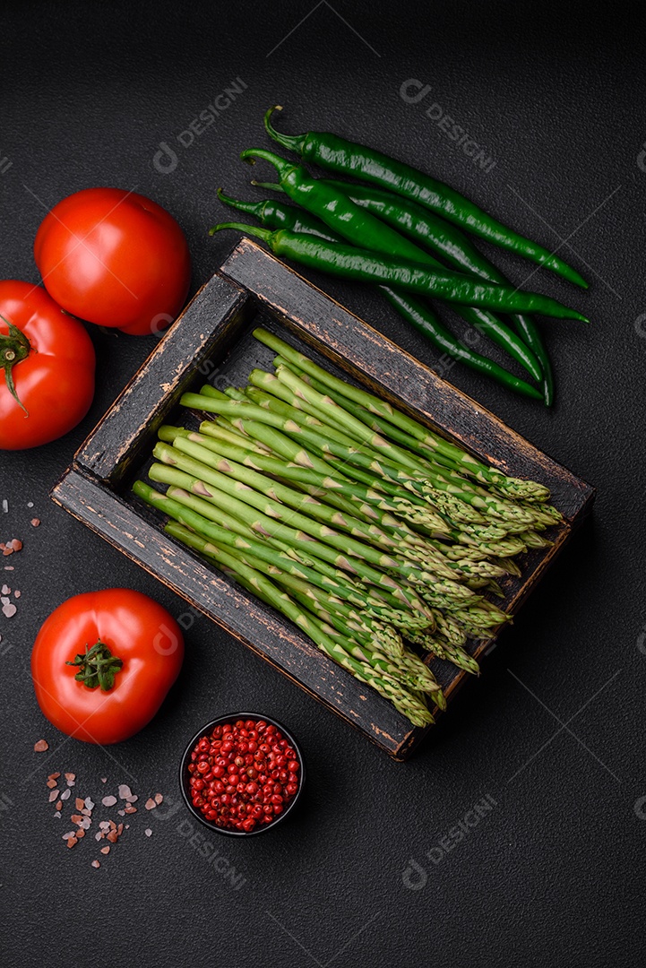 Deliciosos raminhos frescos de aspargos em um fundo escuro texturizado. Ingredientes para uma refeição vegetariana saudável