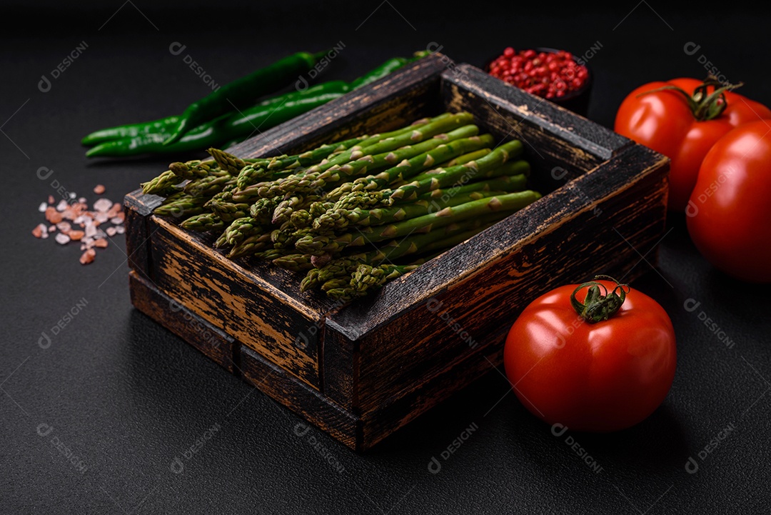 Deliciosos raminhos frescos de aspargos em um fundo escuro texturizado. Ingredientes para uma refeição vegetariana saudável