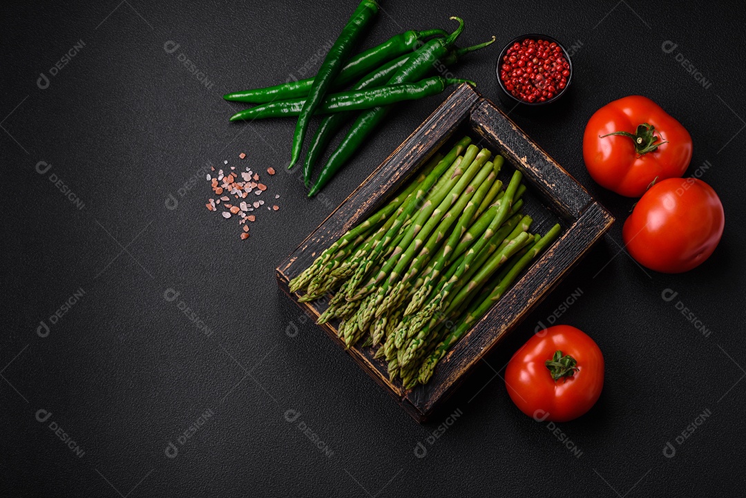 Deliciosos raminhos frescos de aspargos em um fundo escuro texturizado. Ingredientes para uma refeição vegetariana saudável