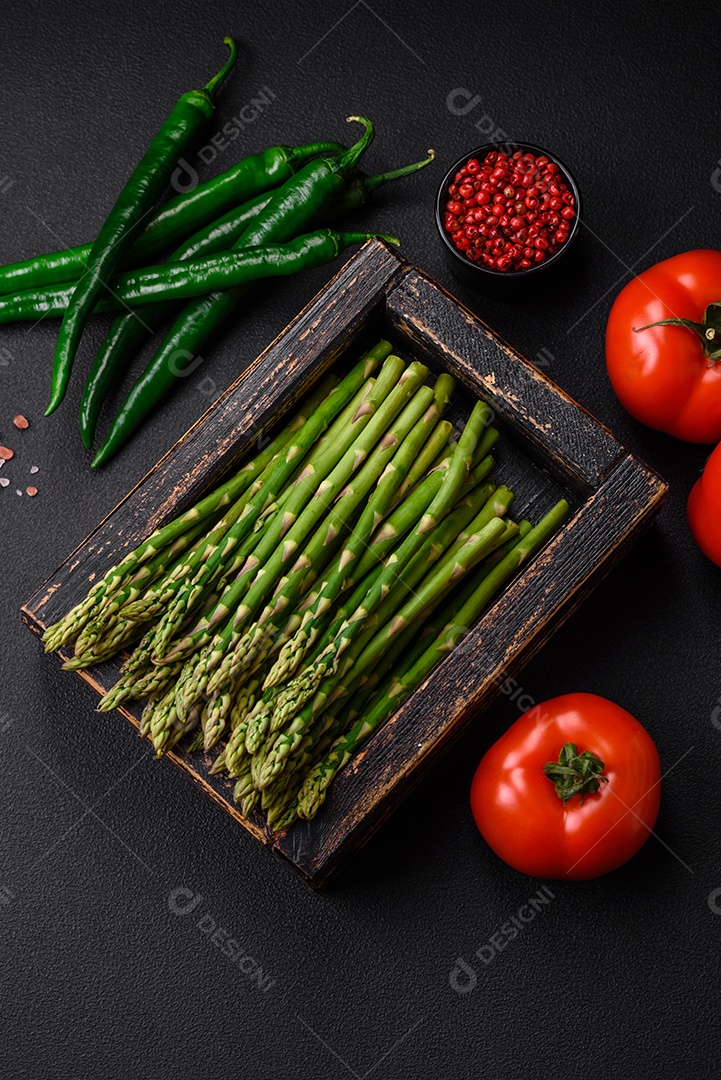 Deliciosos raminhos frescos de aspargos em um fundo escuro texturizado. Ingredientes para uma refeição vegetariana saudável