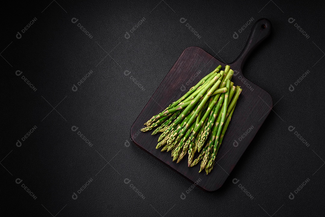 Deliciosos raminhos frescos de aspargos em um fundo escuro texturizado. Ingredientes para uma refeição vegetariana saudável