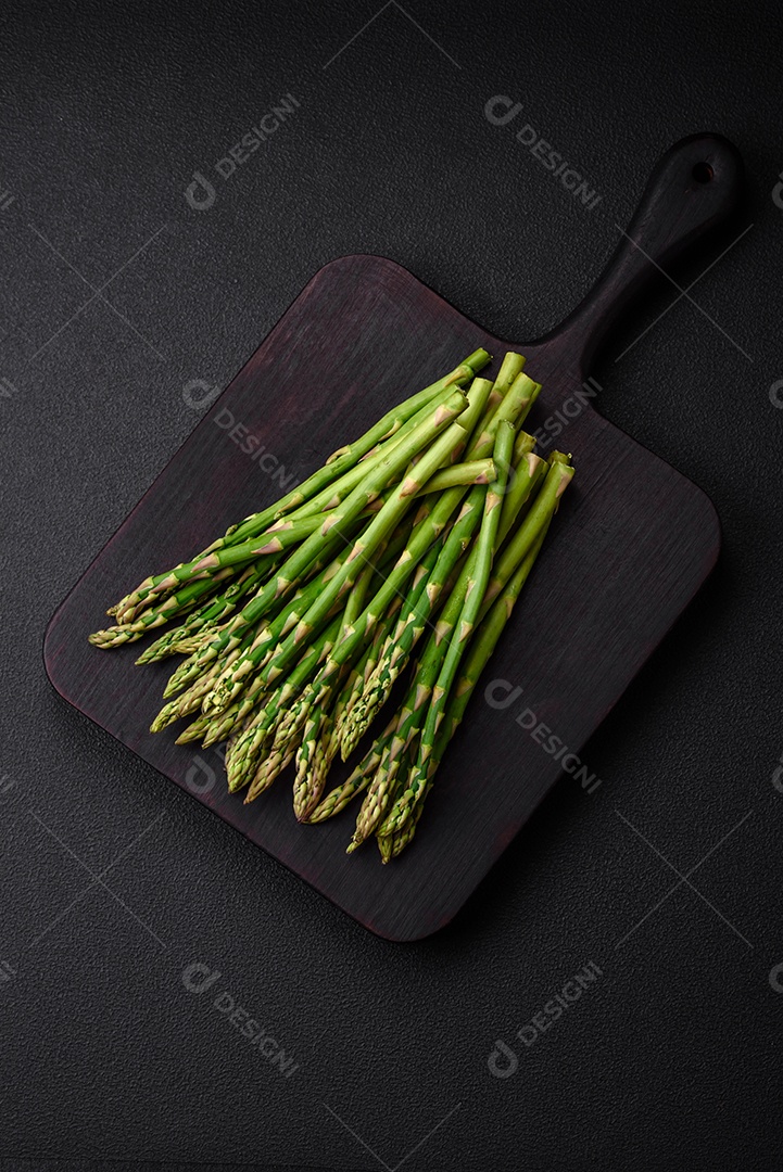 Deliciosos raminhos frescos de aspargos em um fundo escuro texturizado. Ingredientes para uma refeição vegetariana saudável