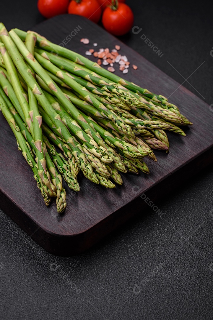 Deliciosos raminhos frescos de aspargos em um fundo escuro texturizado. Ingredientes para uma refeição vegetariana saudável