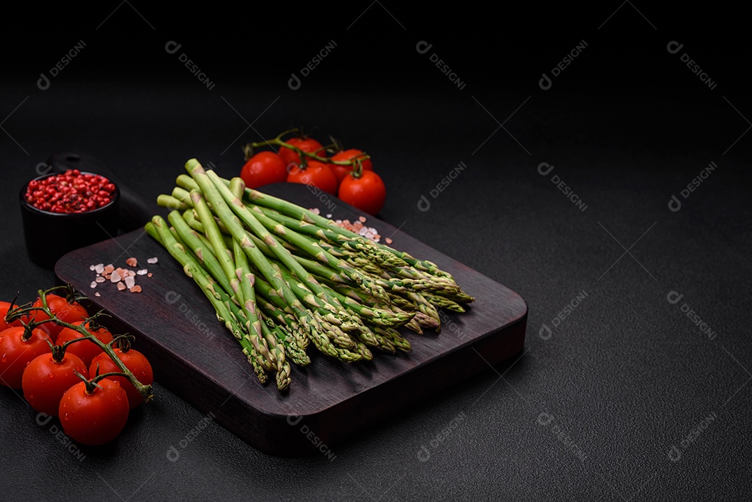 Deliciosos raminhos frescos de aspargos em um fundo escuro texturizado. Ingredientes para uma refeição vegetariana saudável