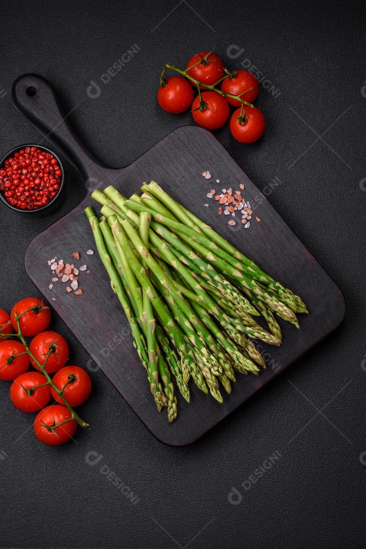Deliciosos raminhos frescos de aspargos em um fundo escuro texturizado. Ingredientes para uma refeição vegetariana saudável