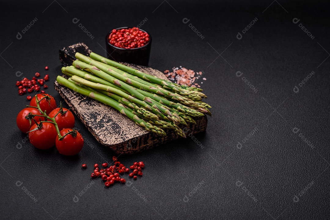 Deliciosos raminhos frescos de aspargos em um fundo escuro texturizado. Ingredientes para uma refeição vegetariana saudável