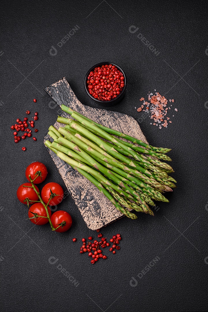 Deliciosos raminhos frescos de aspargos em um fundo escuro texturizado. Ingredientes para uma refeição vegetariana saudável