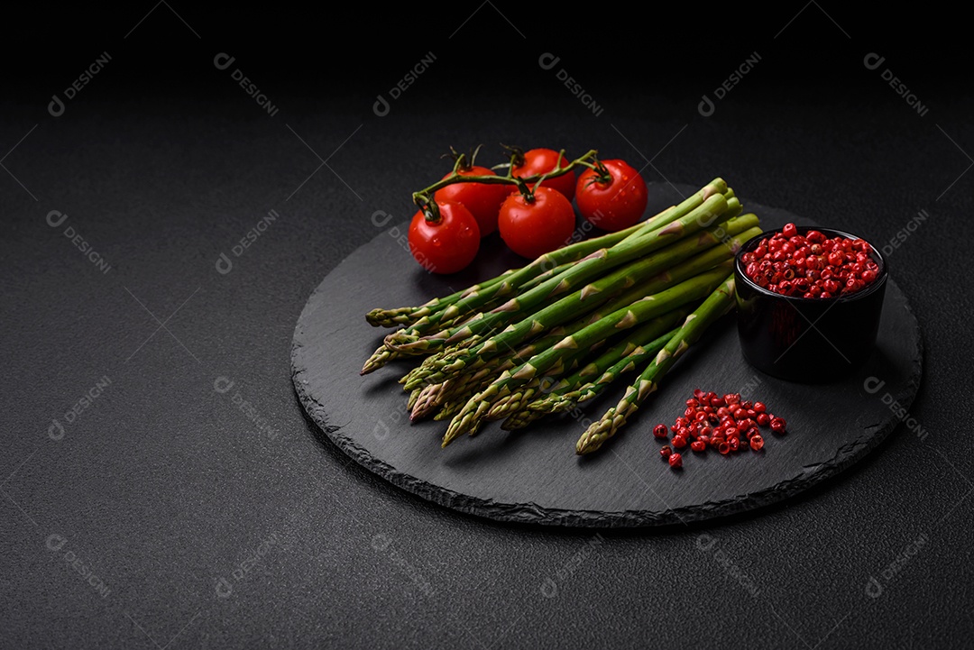 Deliciosos raminhos frescos de aspargos em um fundo escuro texturizado. Ingredientes para uma refeição vegetariana saudável