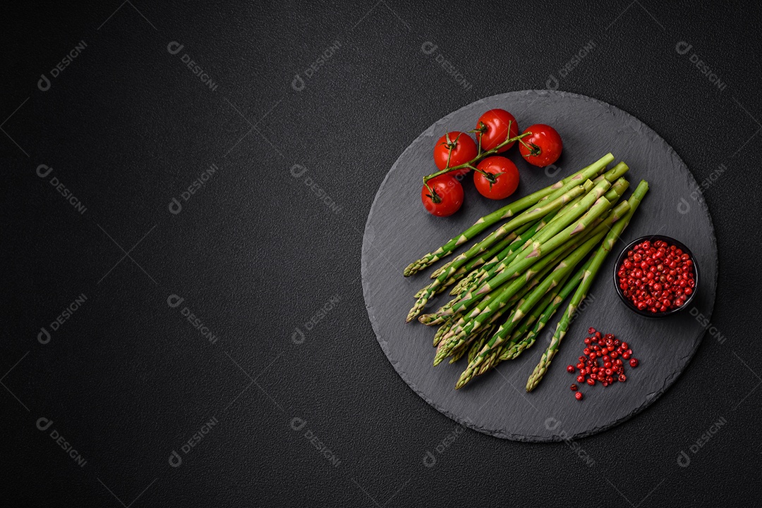Deliciosos raminhos frescos de aspargos em um fundo escuro texturizado. Ingredientes para uma refeição vegetariana saudável