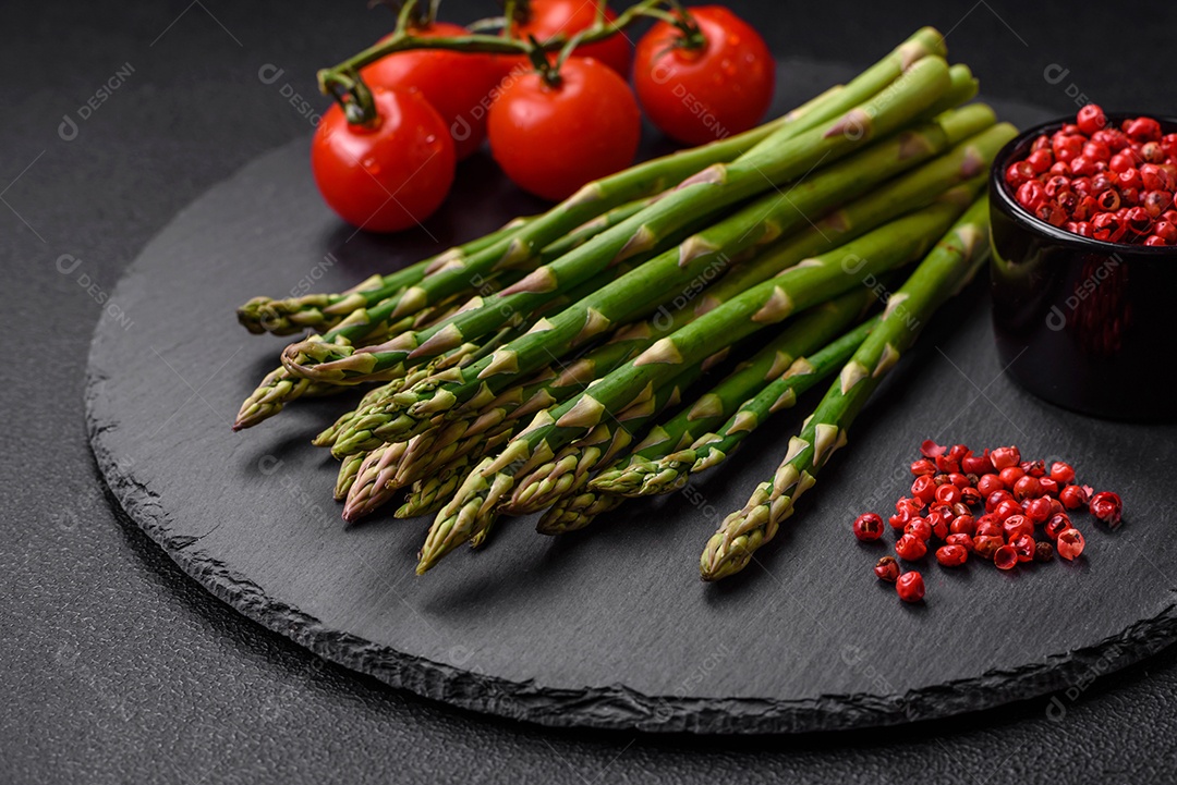 Deliciosos raminhos frescos de aspargos em um fundo escuro texturizado. Ingredientes para uma refeição vegetariana saudável