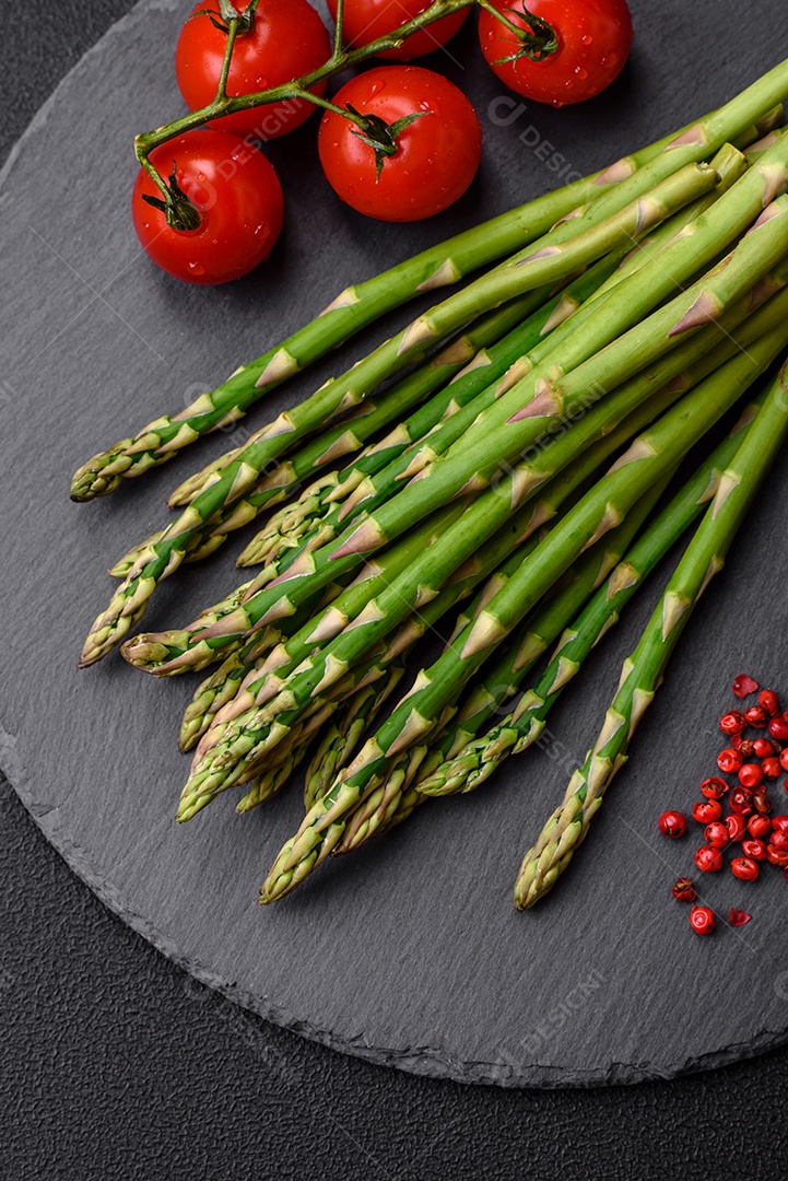 Deliciosos raminhos frescos de aspargos em um fundo escuro texturizado. Ingredientes para uma refeição vegetariana saudável