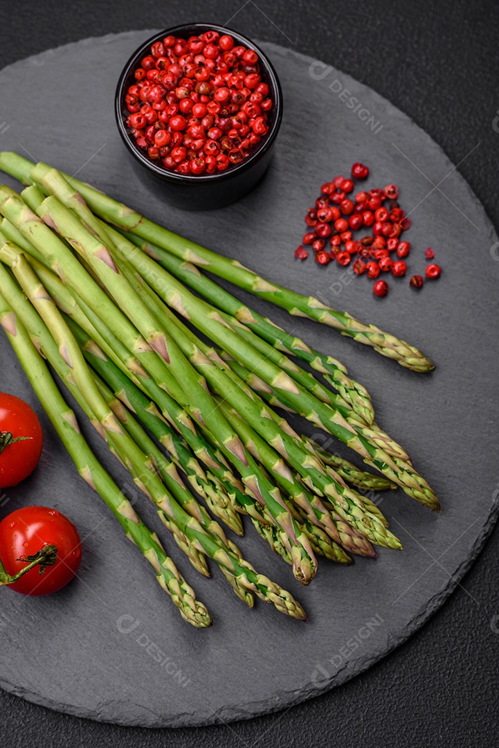 Deliciosos raminhos frescos de aspargos em um fundo escuro texturizado. Ingredientes para uma refeição vegetariana saudável