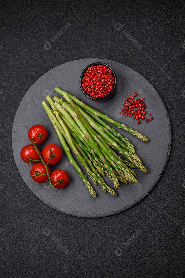 Deliciosos raminhos frescos de aspargos em um fundo escuro texturizado. Ingredientes para uma refeição vegetariana saudável