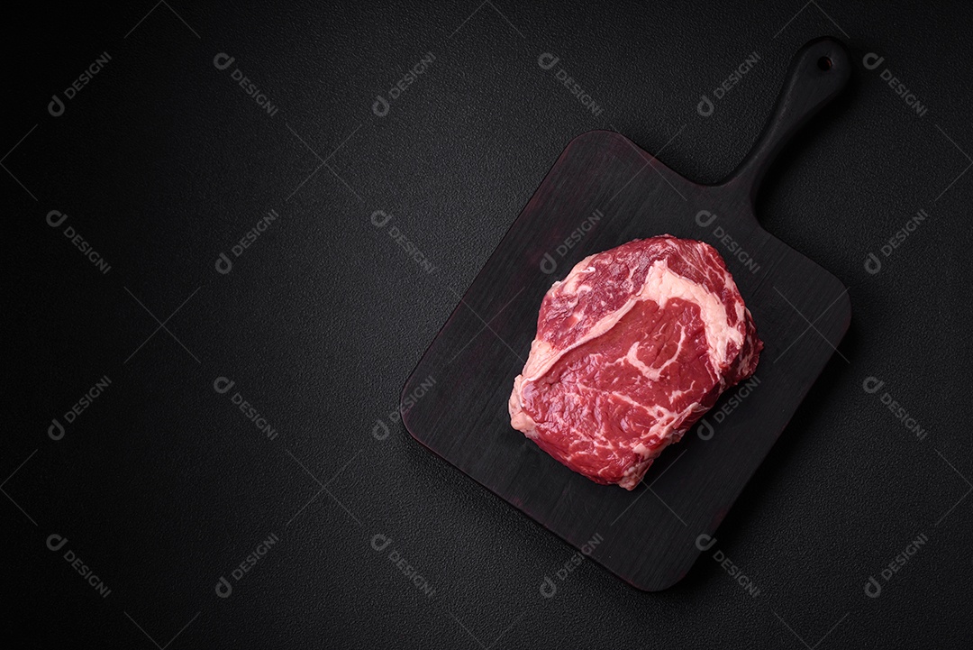 Bife fresco e cru com sal, especiarias e ervas em um fundo escuro e texturizado