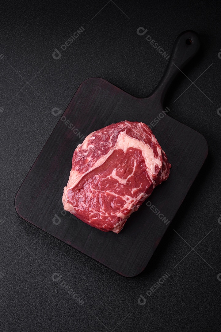 Bife fresco e cru com sal, especiarias e ervas em um fundo escuro e texturizado