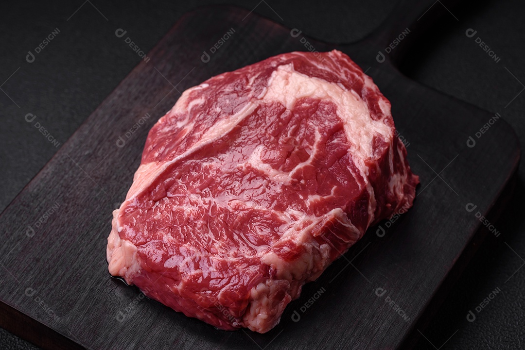 Bife fresco e cru com sal, especiarias e ervas em um fundo escuro e texturizado