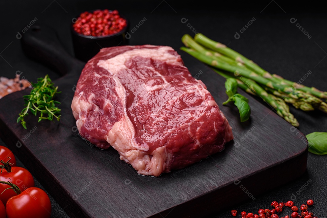 Bife fresco e cru com sal, especiarias e ervas em um fundo escuro e texturizado