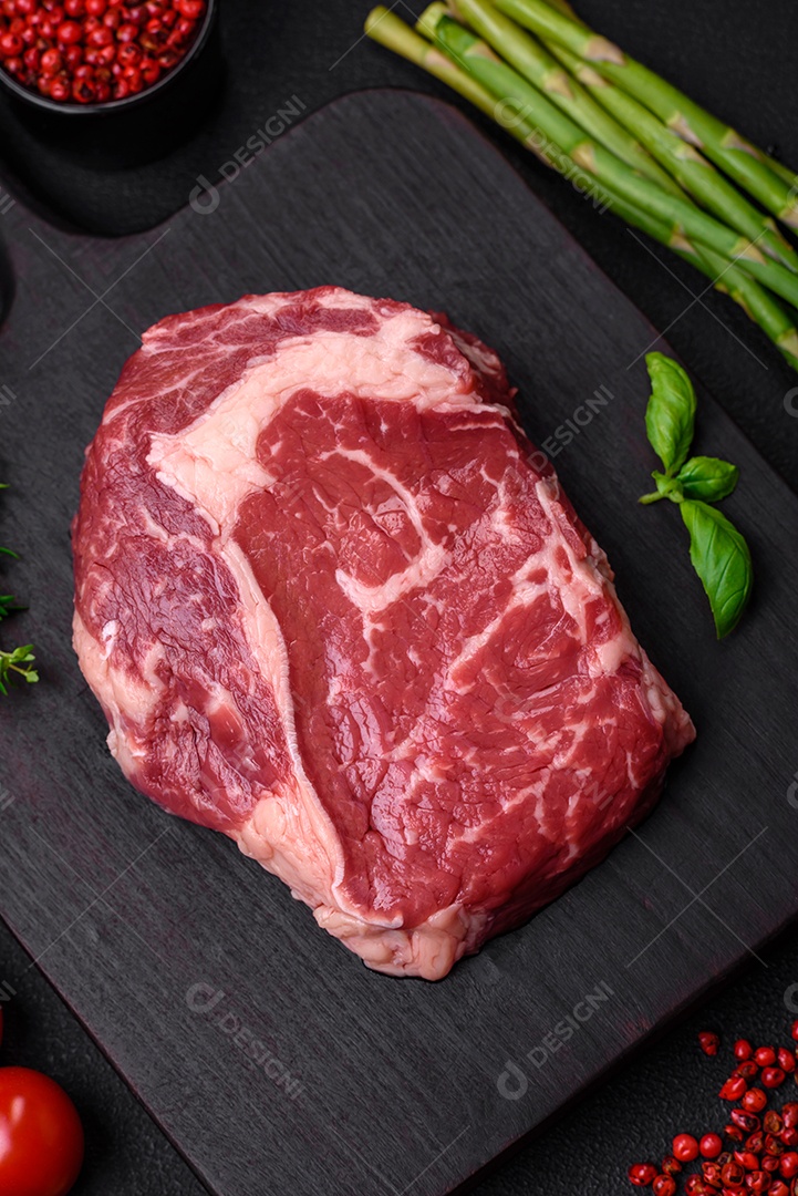 Bife fresco e cru com sal, especiarias e ervas em um fundo escuro e texturizado