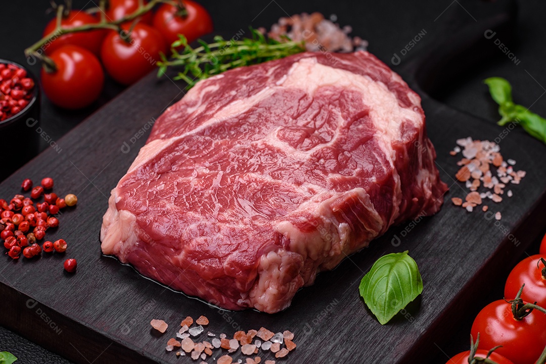 Bife fresco e cru com sal, especiarias e ervas em um fundo escuro e texturizado