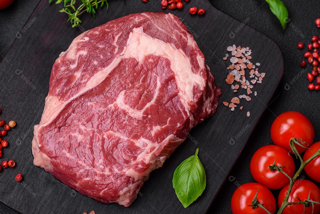 Bife fresco e cru com sal, especiarias e ervas em um fundo escuro e texturizado