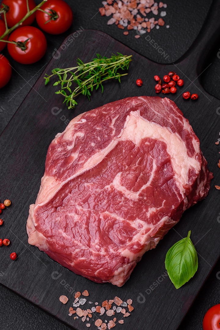 Bife fresco e cru com sal, especiarias e ervas em um fundo escuro e texturizado