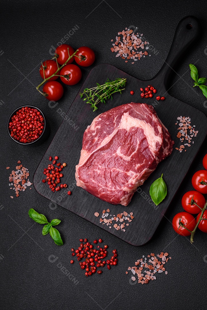 Bife fresco e cru com sal, especiarias e ervas em um fundo escuro e texturizado