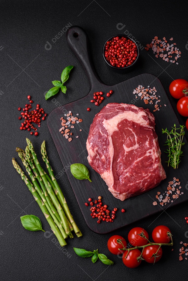 Bife fresco e cru com sal, especiarias e ervas em um fundo escuro e texturizado