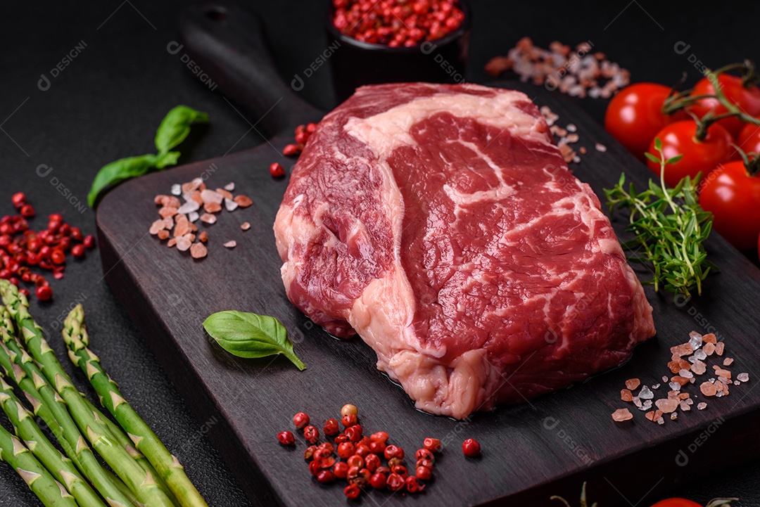 Bife fresco e cru com sal, especiarias e ervas em um fundo escuro e texturizado