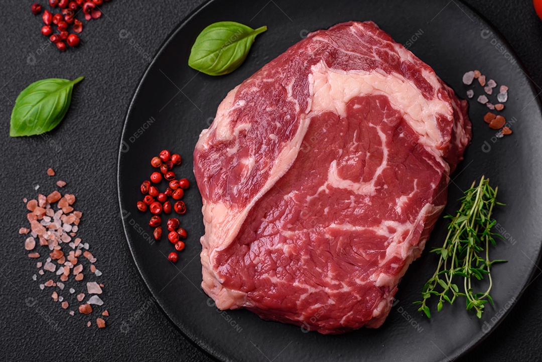 Bife fresco e cru com sal, especiarias e ervas em um fundo escuro e texturizado