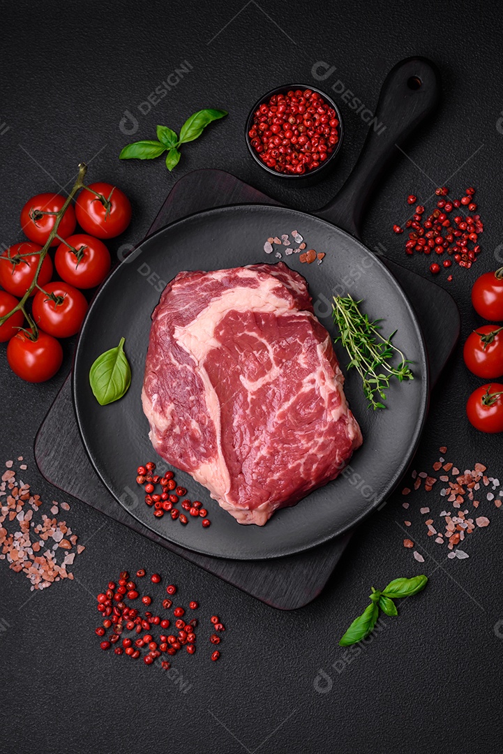Bife fresco e cru com sal, especiarias e ervas em um fundo escuro e texturizado