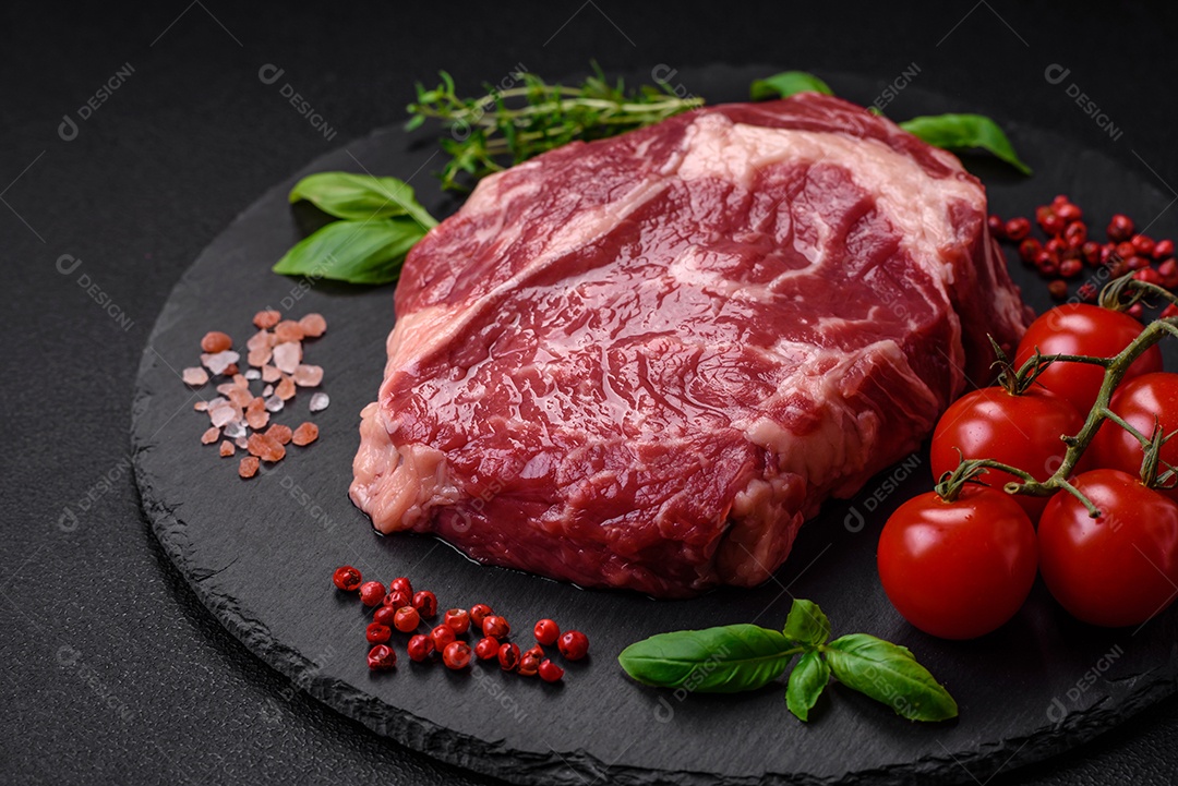 Bife fresco e cru com sal, especiarias e ervas em um fundo escuro e texturizado
