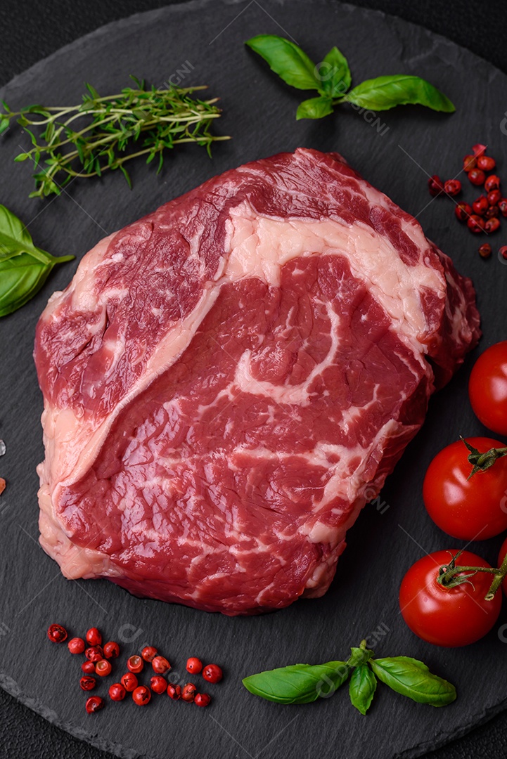 Bife fresco e cru com sal, especiarias e ervas em um fundo escuro e texturizado