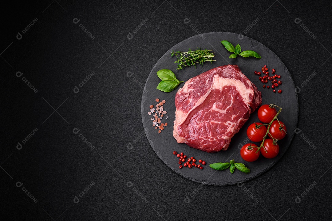 Bife fresco e cru com sal, especiarias e ervas em um fundo escuro e texturizado