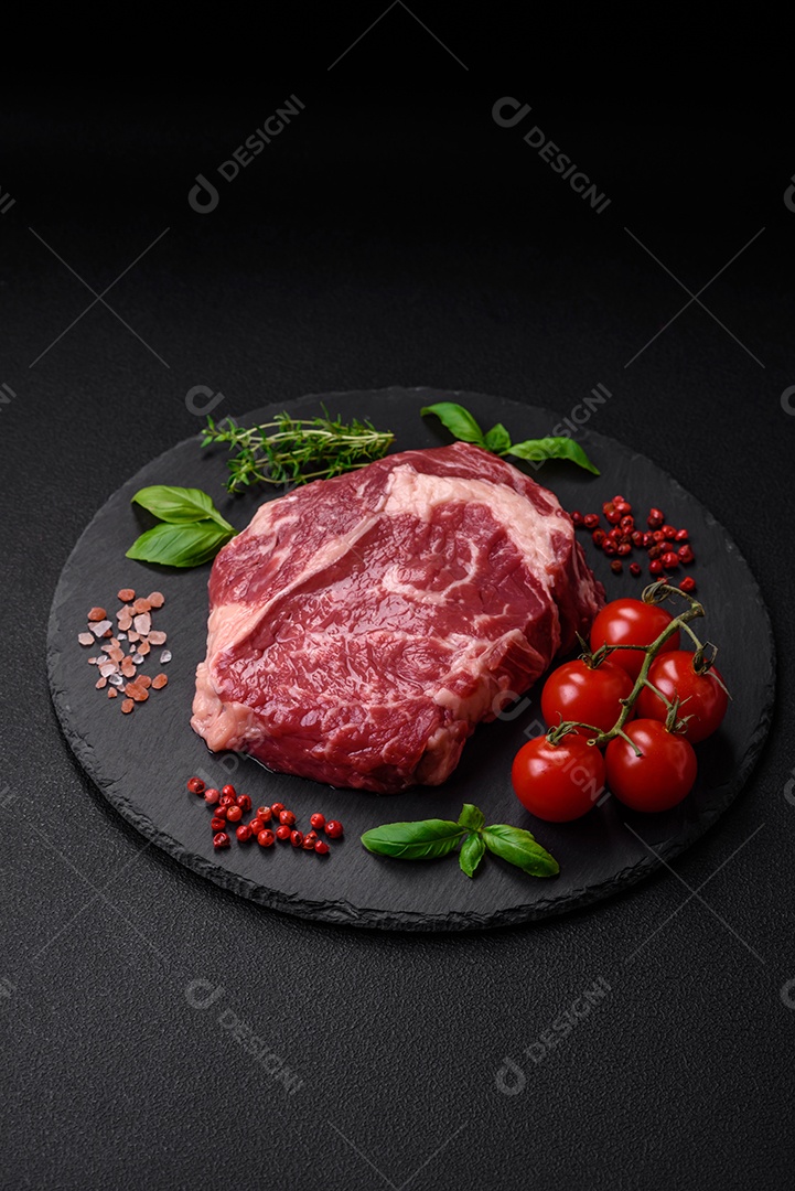 Bife fresco e cru com sal, especiarias e ervas em um fundo escuro e texturizado
