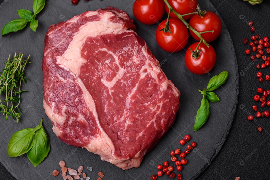 Bife fresco e cru com sal, especiarias e ervas em um fundo escuro e texturizado