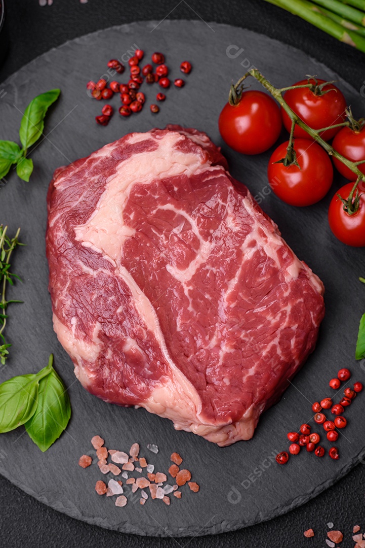 Bife fresco e cru com sal, especiarias e ervas em um fundo escuro e texturizado