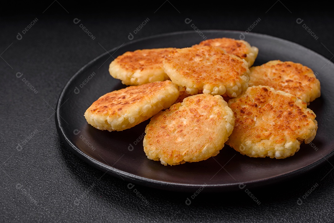 Deliciosos cheesecakes frescos com passas e baunilha em uma placa de cerâmica preta sobre um fundo escuro de concreto