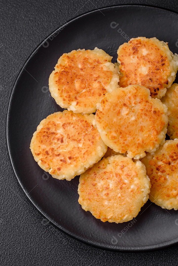 Deliciosos cheesecakes frescos com passas e baunilha em uma placa de cerâmica preta sobre um fundo escuro de concreto