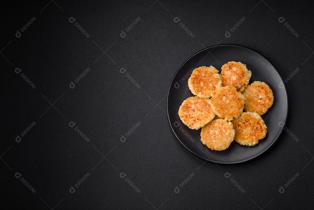 Deliciosos cheesecakes frescos com passas e baunilha em uma placa de cerâmica preta sobre um fundo escuro de concreto